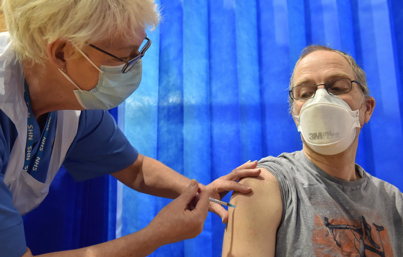  08 December 2020, Wales, Cardiff: David Farrell receives the Pfizer/BioNtech vaccine in a vaccination centre on the first day of the largest immunisation programme in the UK's history. Photo: Ben Birchall/PA Wire/dpa - Ben Birchall/PA Wire/dpa 