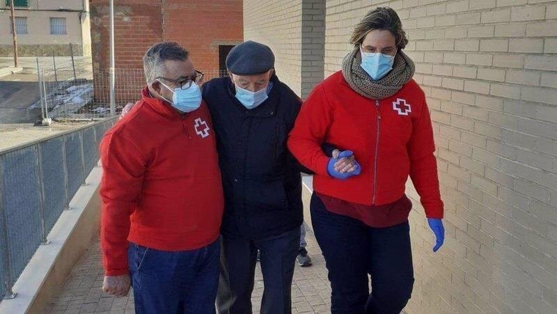  Miembros de Cruz Roja con un anciano. // EP 