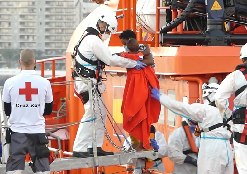  Un miembro de la Cruz Roja ayuda a bajar del barco a una mujer migrante con su niño en el puerto de Arguineguín - Europa Press 