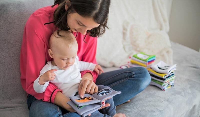 <p> Una madre con su bebé mirando un libro infantil. </p>