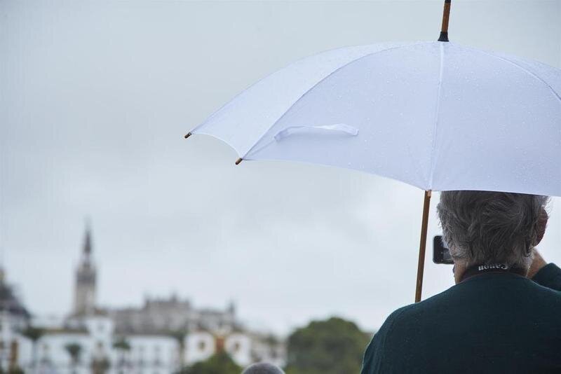 <p> Un señor, bajo su paraguas, toma una foto con su móvil del río Guadalquivir en un día lluvioso del puente de Todos los Santos el 30 de octubre de 2021 en Sevilla (Andalucía, España) - Joaquin Corchero - Europa Press </p>