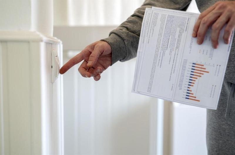 <p> Un hombre enciende un interruptor con una factura de luz en la mano, a 3 de enero de 2022 </p>