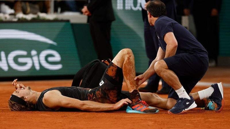 <p> Zverev en el suelo de Roland Garros, siendo atendido tras su lesión </p>