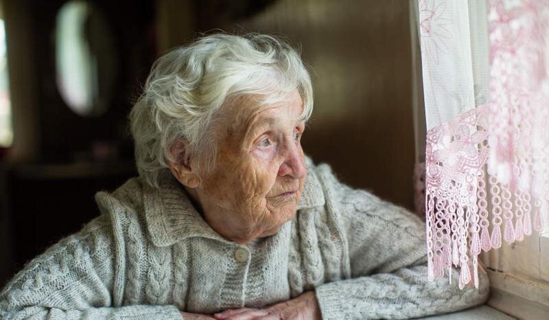 <p> Mujer mayor mirando por la ventana </p>