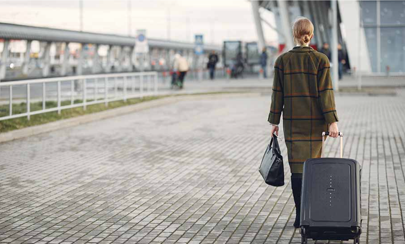  Una mujer camina con su maleta camino del aeropuerto. 