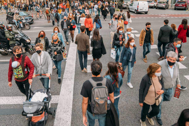 Barcelona, Spain - APR 23 2021: Crowd walking in Rambla Catalunya on Sant Jordi day. Sant Jordi's festivity is a catalan tradition where people buy books and red roses to give each other. This day the streets of Barcelona were crowded with people wearing masks because of Covid-19