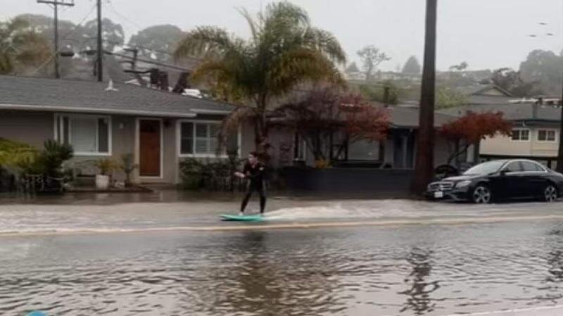  El joven haciendo esquí acuático en una calle inundada 