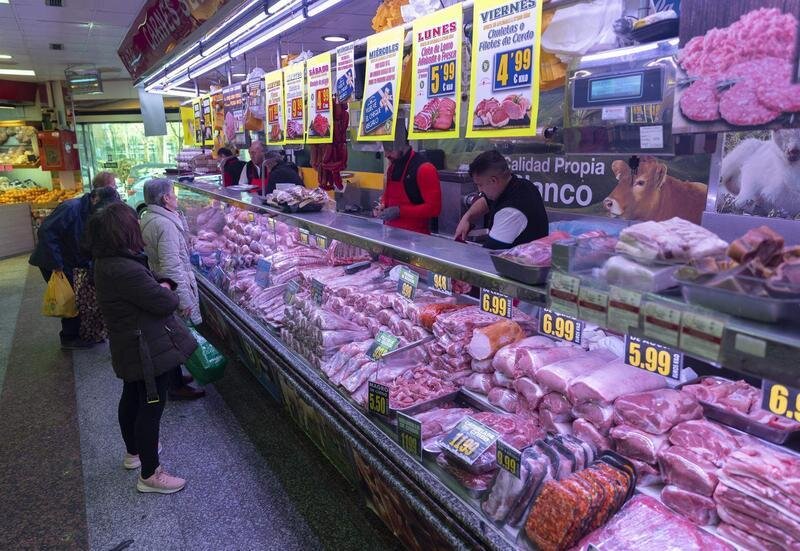  Varias personas compran en una carnicería en un mercado 