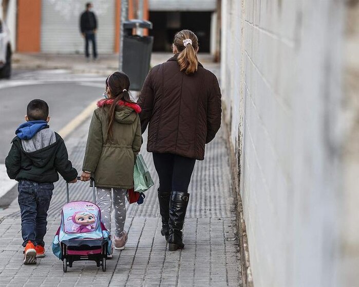  Un niño y una niña, acompañados de una mujer, caminan hacia el colegio público CEIP Antonio Machado 