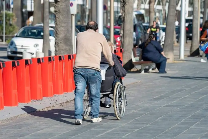  Una persona acompañando a otra en silla de ruedas 