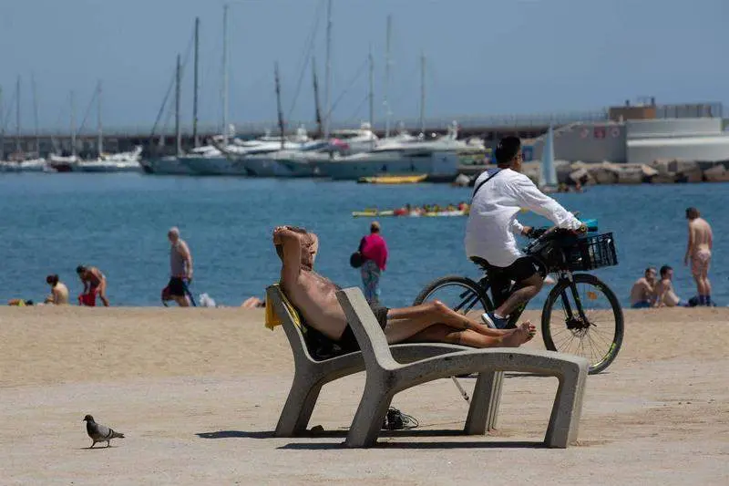  Varias personas toman el sol en la playa de la Barceloneta, a 13 de julio de 2022 