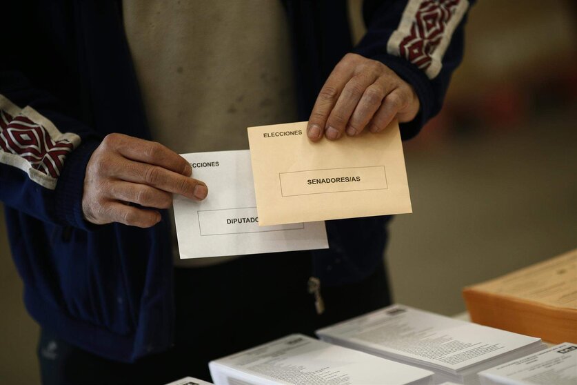  Un elector sostiene sus sobres de vortación para las generales 