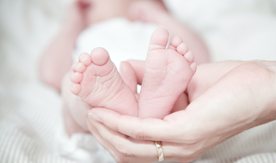  Las manos de una madre sostienen los pies de su bebé. 