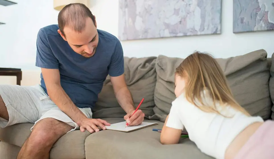  Un padre realiza una tarea escolar junto a su hija. 