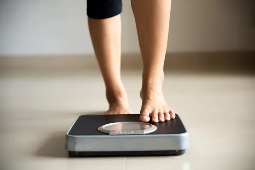  Female leg stepping on weigh scales. Healthy lifestyle, food and sport concept. 